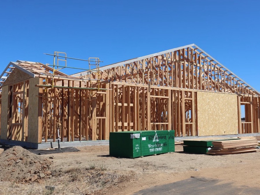 New timber framing for a house and garage against a clear blue sky.